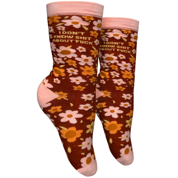 I Don't Know S**t About F**k Socks - Small. A pair of socks with a bold sweary slogan and a bold flowers design. Pink toes, hell and cuff. 