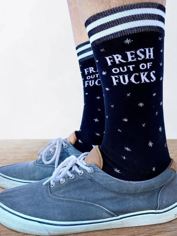 Fresh out of F**ks Socks. Model wearing pair of socks with a bold slogan and simple black and purple stars design. Purple toes, heel and cuff.