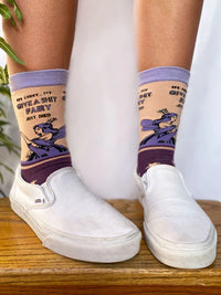 Model wearing a pair of socks with a bold slogan and a fairy design. Purple feet and light purple toe, hell and cuff.