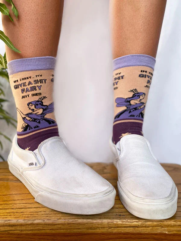 Model wearing a pair of socks with a bold slogan and a fairy design. Purple feet and light purple toe, hell and cuff.