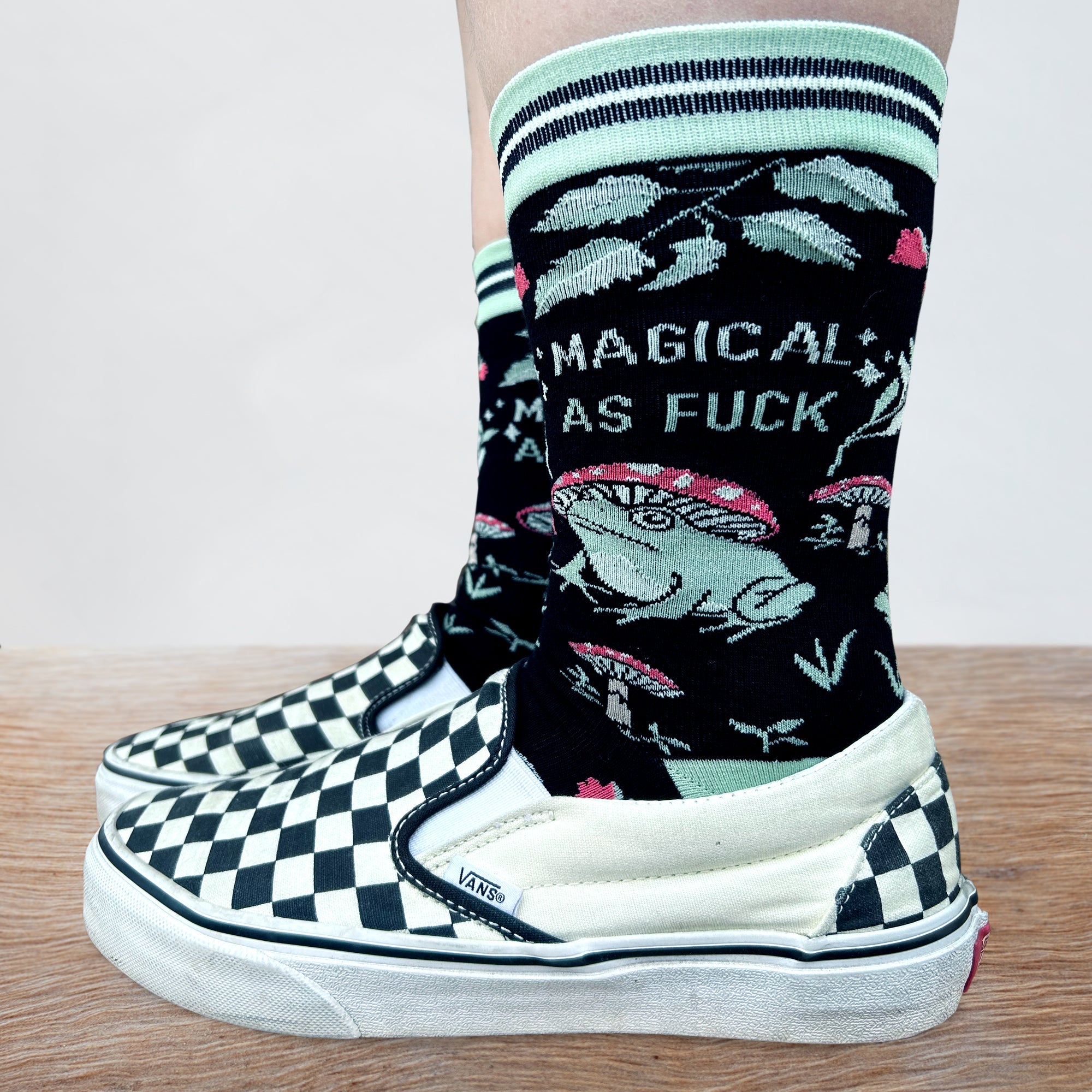 Model wearing a Pair of socks with a fun and sweary slogan. Featuring a magic toad and magic mushroom pattern. Turquoise toe, heel and cuff.